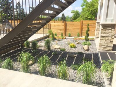 After irrigation installation and landscaping – vibrant greenery and stonework. Calgary backyard after irrigation installation with green plants and landscaping