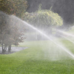 Lawn Sprinkler Spraying Water Over Green Grass in Garden gardening. lawn sprinkler spraying water over green grass in garden